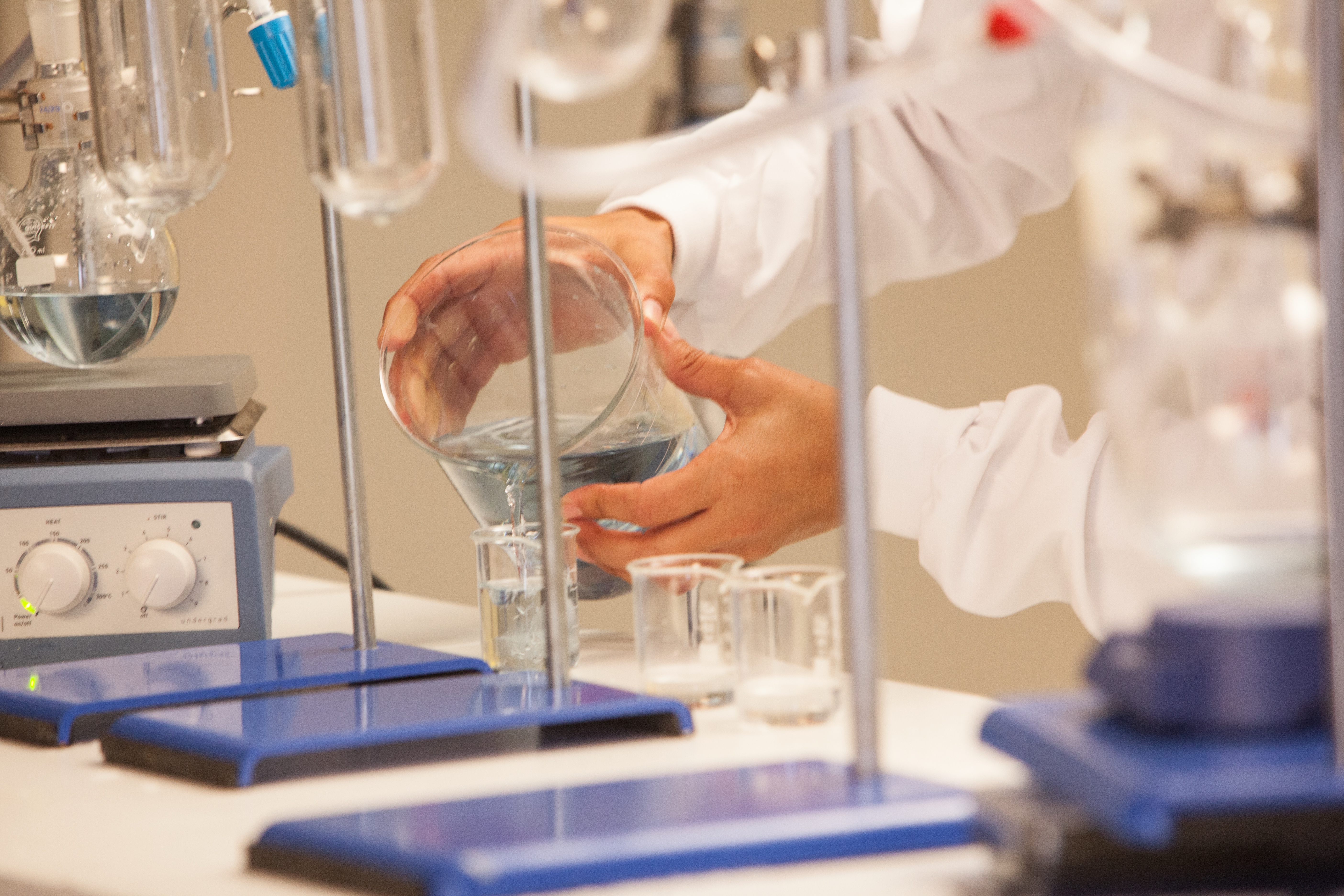 A scientist pouring a liquid into a beaker in a lab