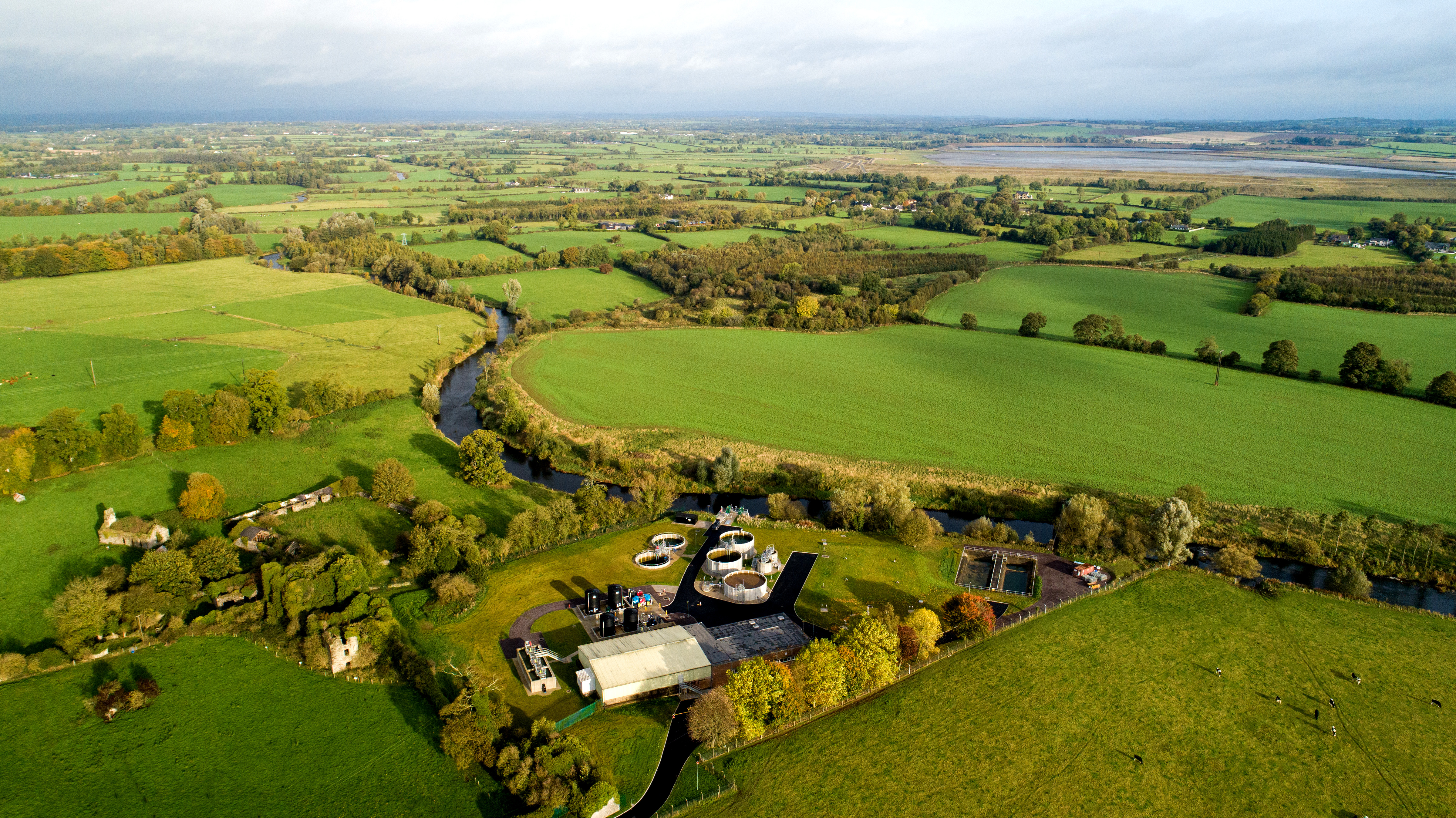 A water treatment plant by a river, several old cottages and many green fields