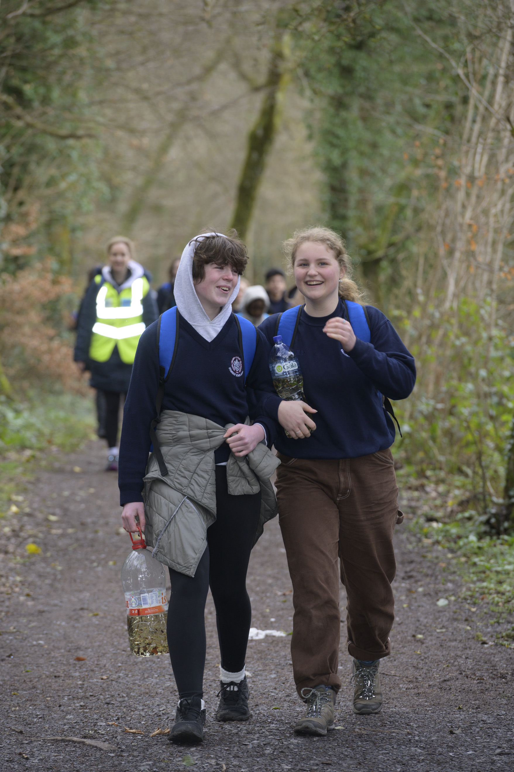 Two schoolchildren talking with each other and holding plastic water bottles of water