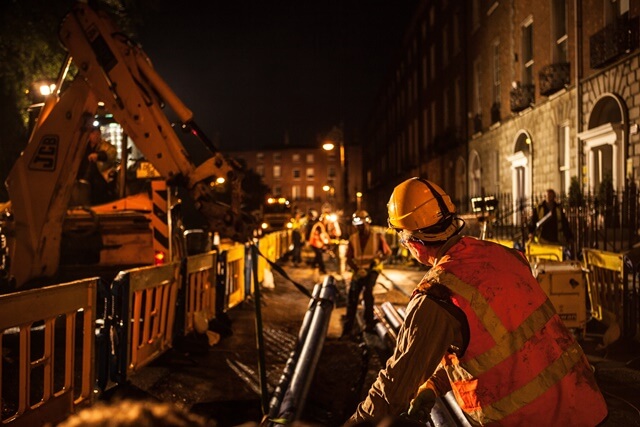 An Uisce Éireann worker working with pipes at night