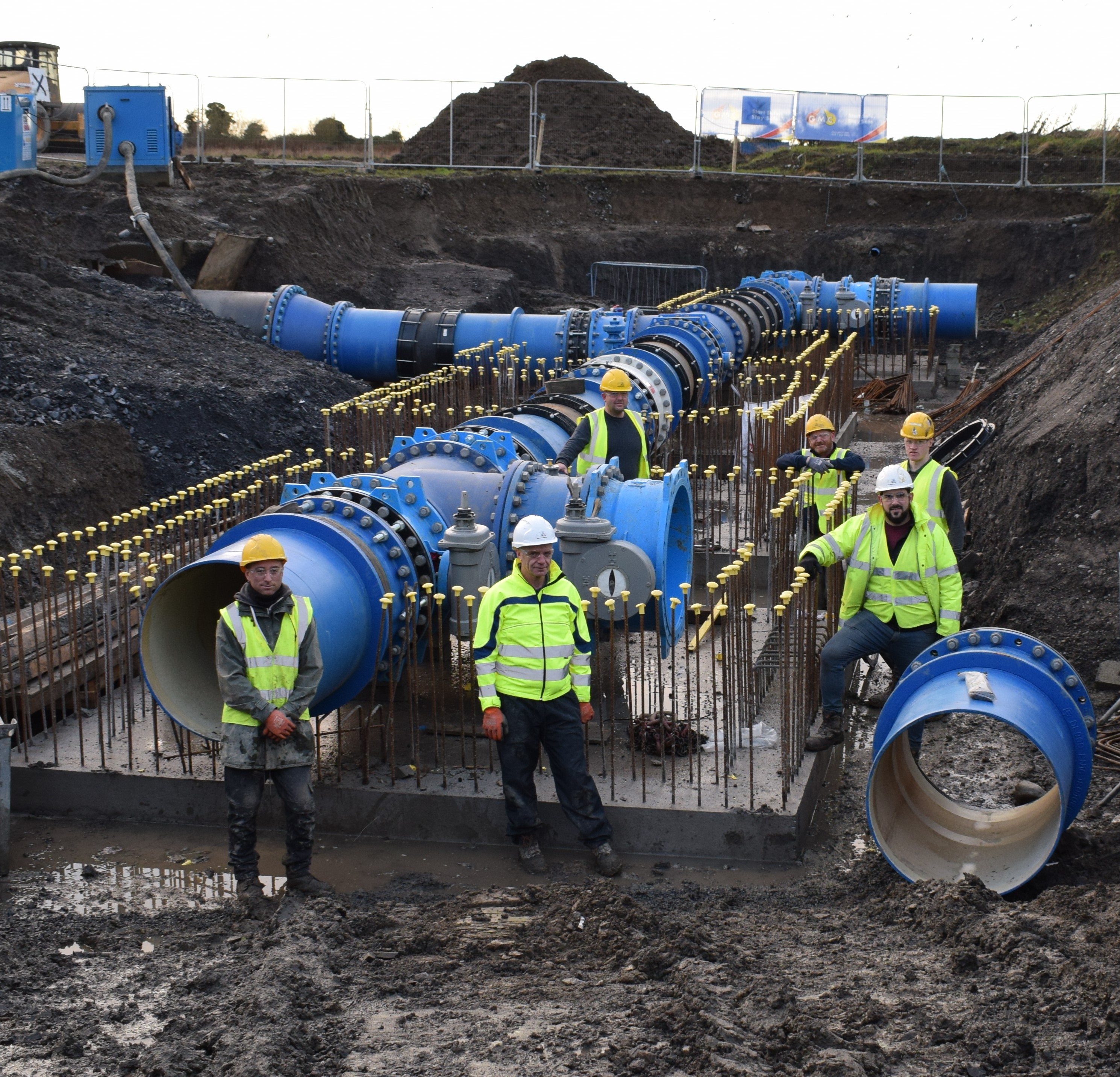 Uisce Éireann workers standing by large pipes on a construction site