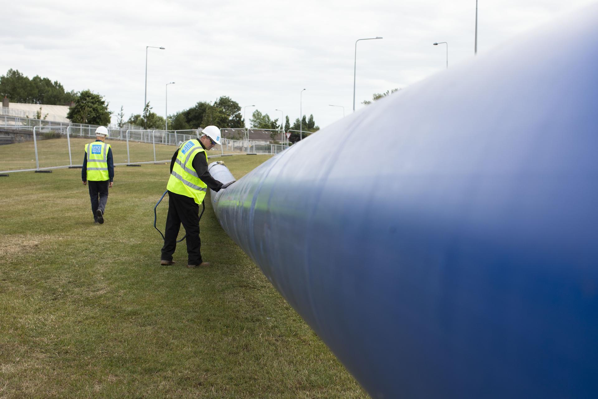 An Uisce Éireann worker working on a large blue pipe