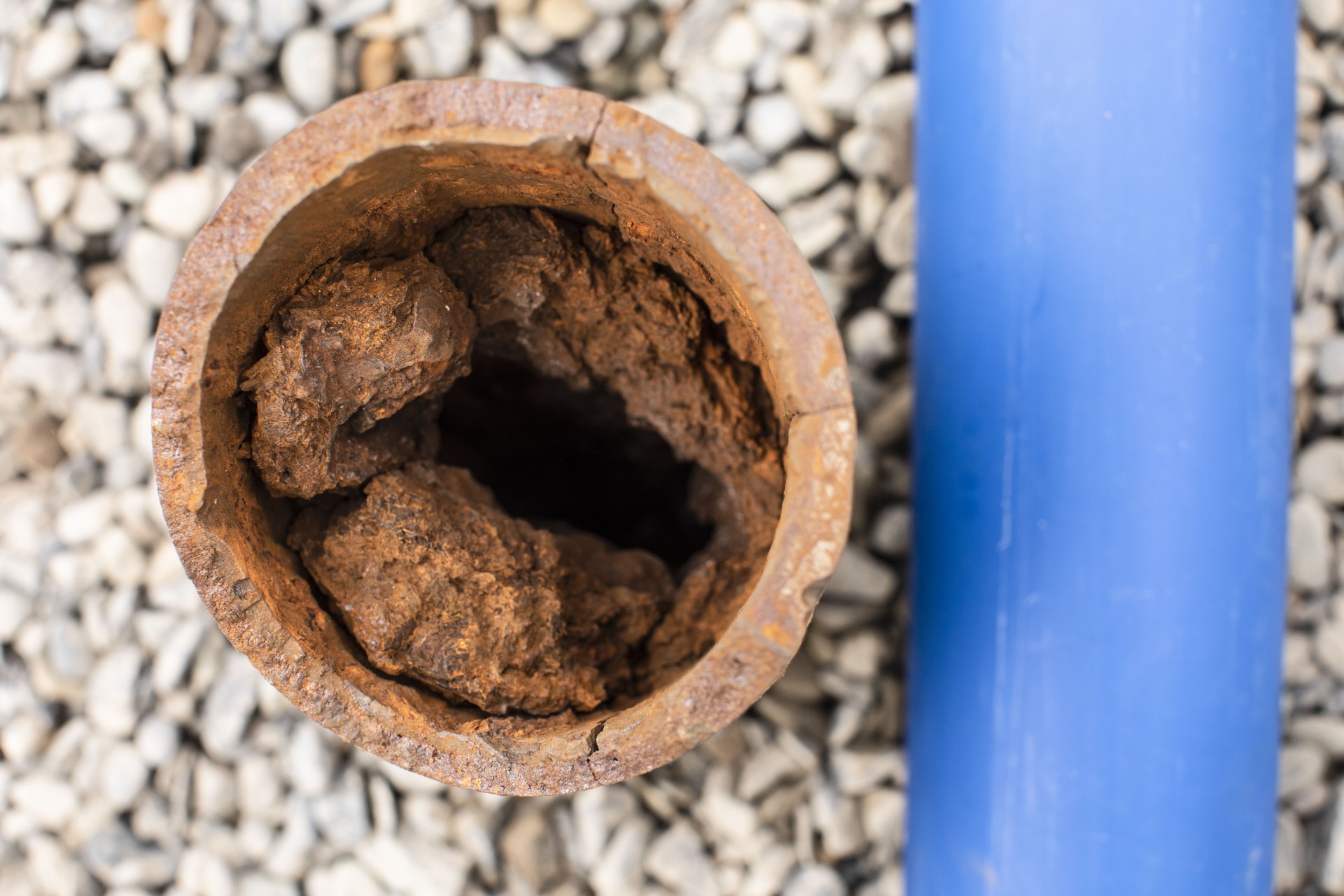 A new clean pipe next to an old cast iron pipe