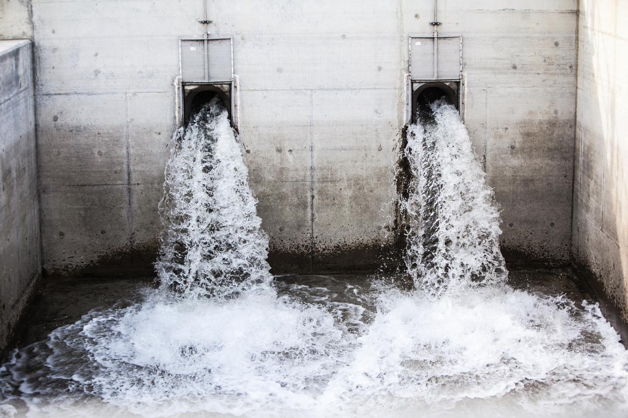 Water flowing out of two large pipes in a wall