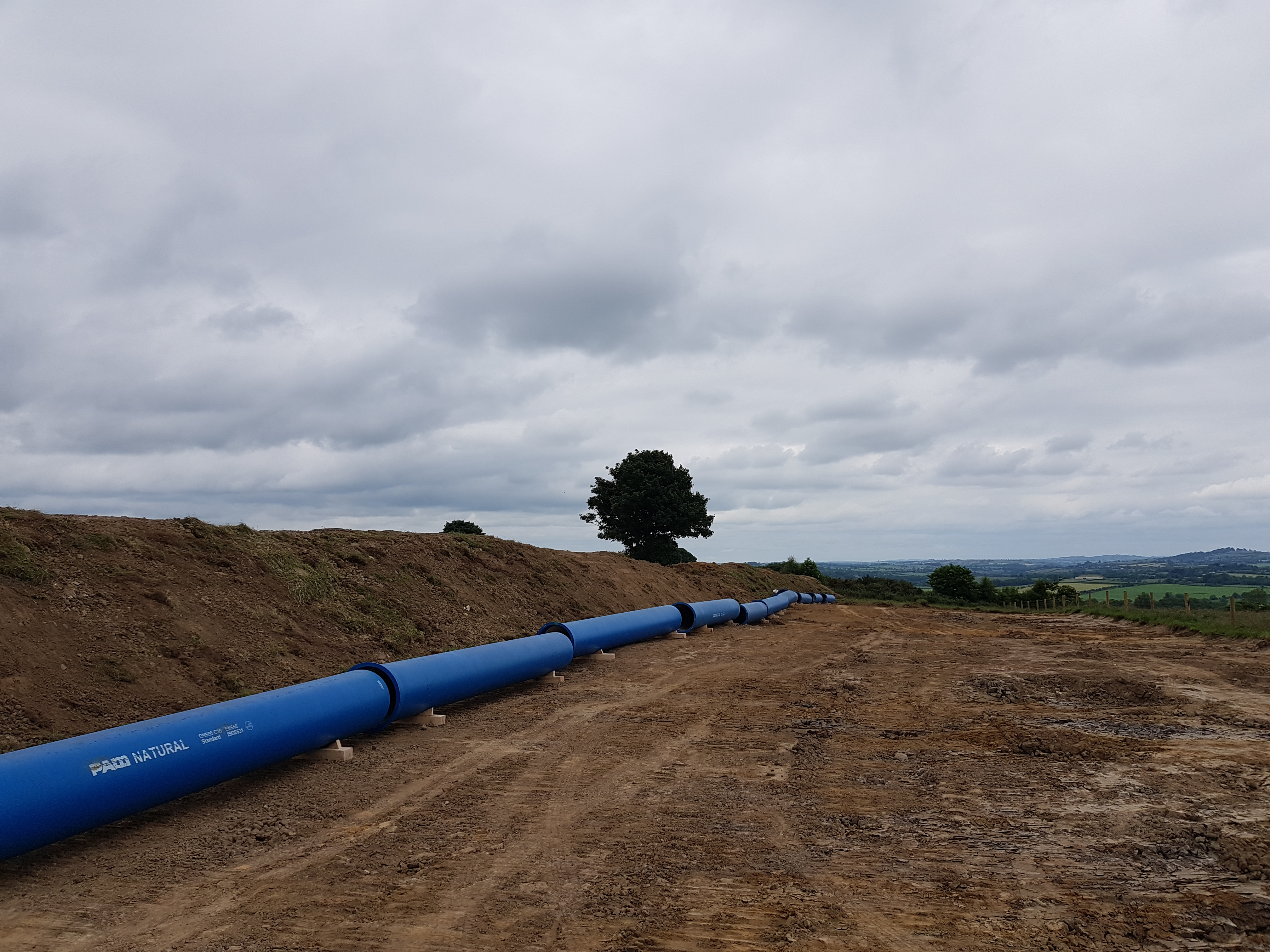 A large blue pipe running across a field of dirt