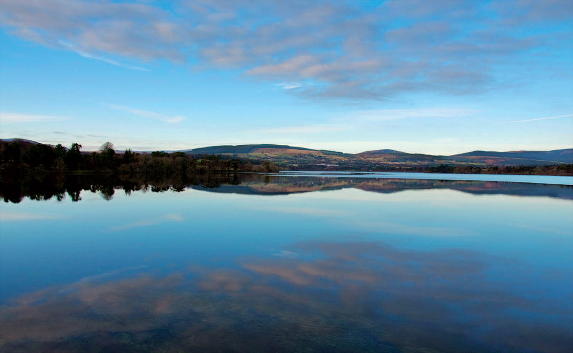 A large blue lake with hills and a forest in the background