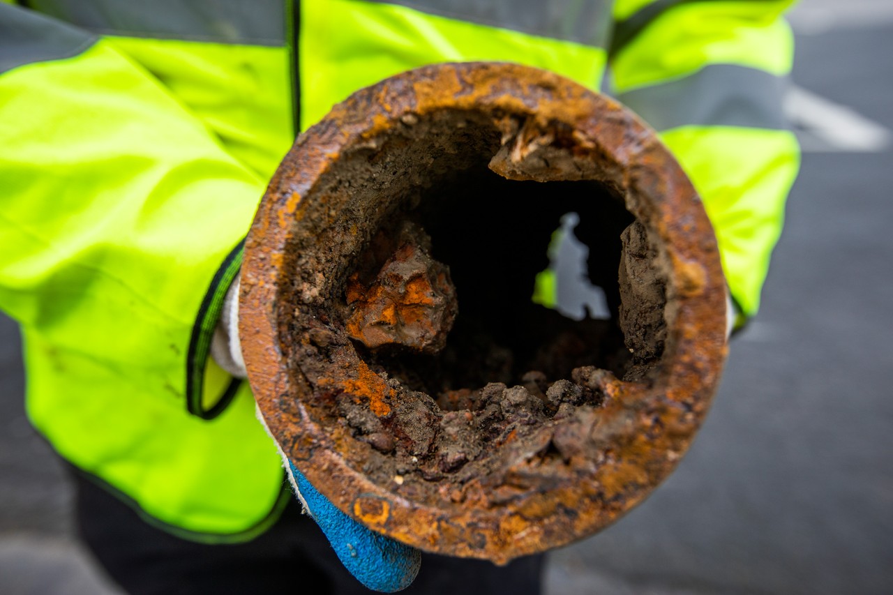 A person holding a rusty and damaged pipe