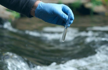 A worker holding a test tube of water for testing