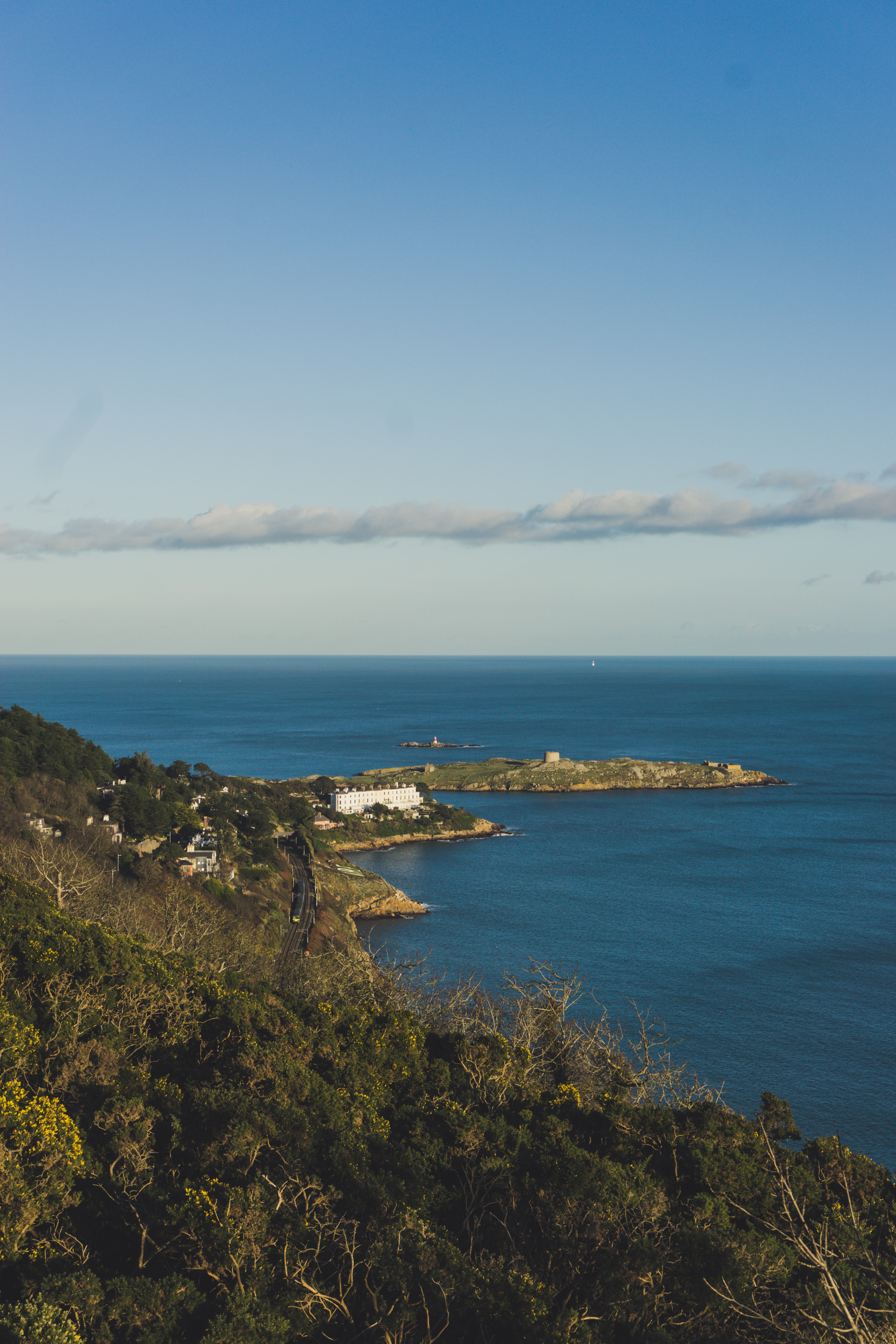 Coastal landscape with a train track, some houses and a small island in the sea