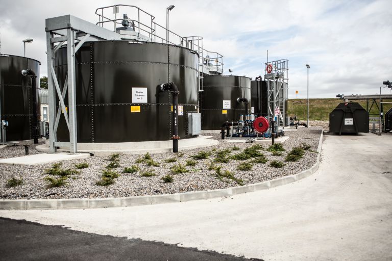 Four large black cylindrical tanks with pipes coming out of them