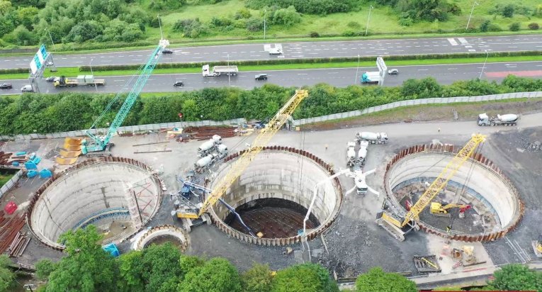 Three large concrete circles in the ground under construction beside the motor way