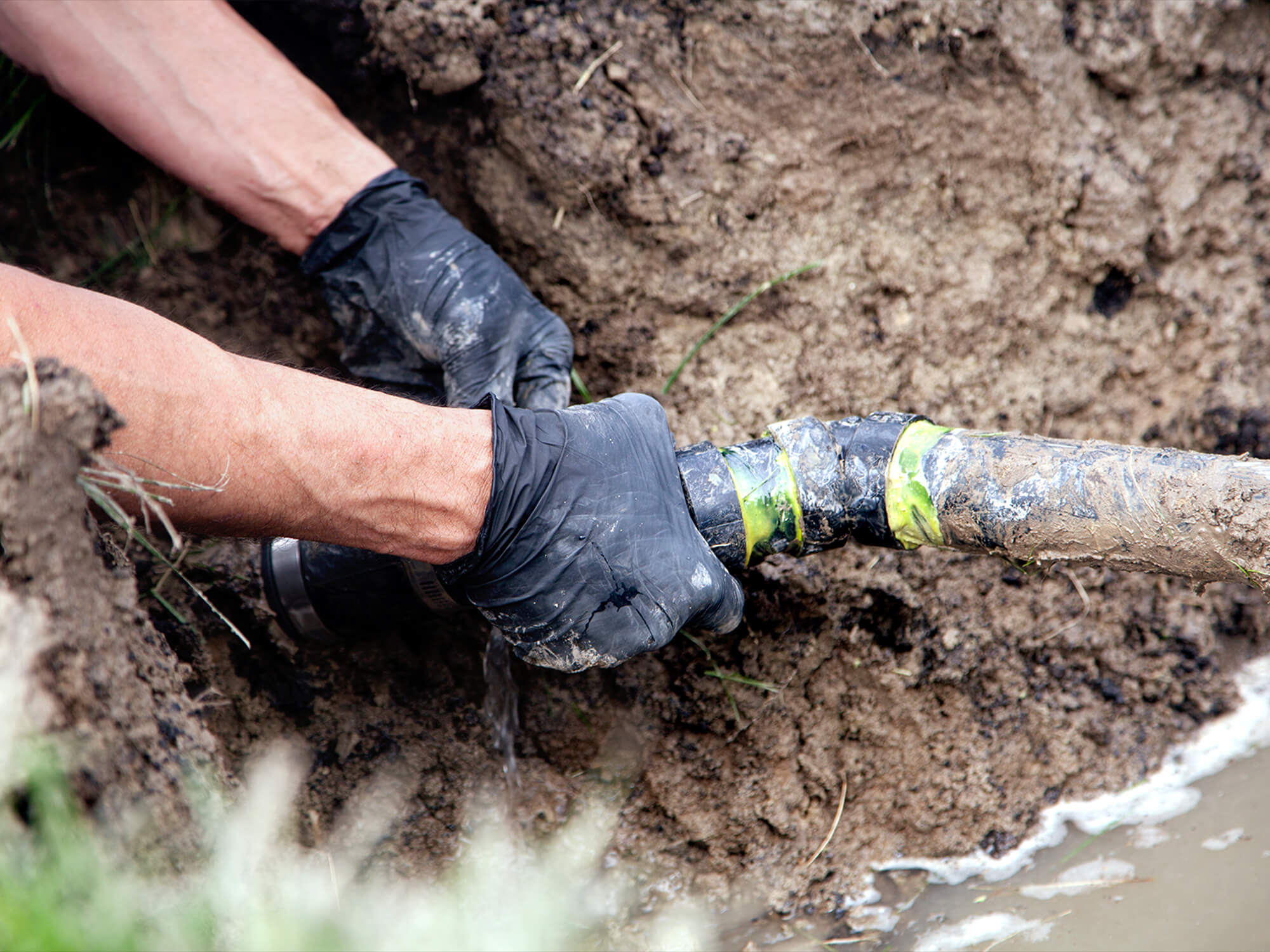 A worker fixing a pipe in the ground