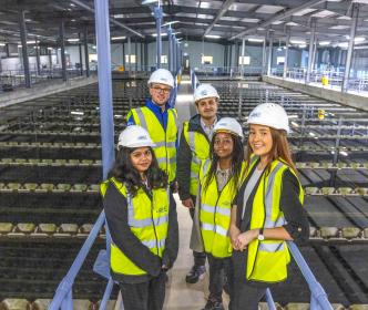 Five graduates wearing safety gear in a water treatment plant