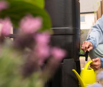 A person filling a watering can in a garden