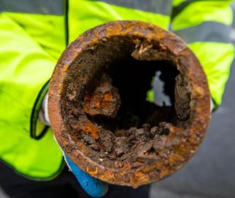 A worker holding an old rusty pipe